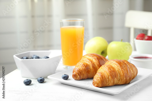 Tasty breakfast with croissants served on white wooden table
