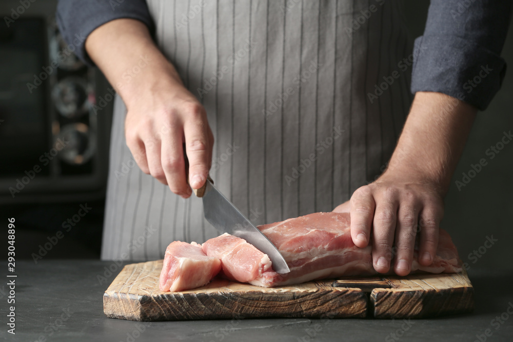 Man cutting fresh raw meat on table, closeup Man cutting fresh raw meat on table, closeup