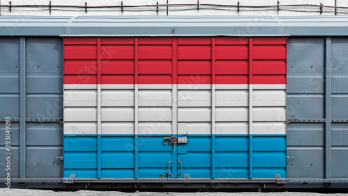 Front view of a container train freight car with a large metal lock with the national flag of Luxemberg.