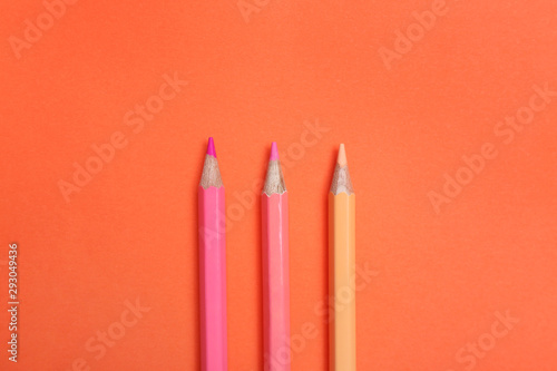 Color pencils on coral background  flat lay
