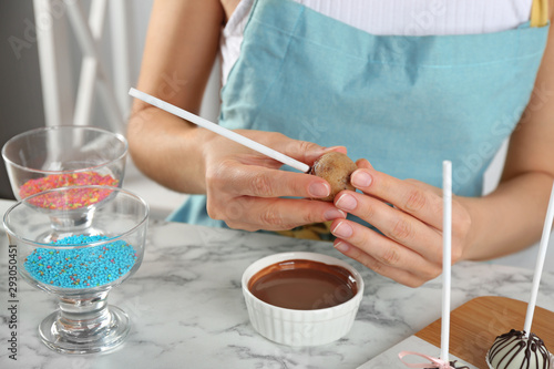 Young woman with cake pop and chocolate frosting at white marble table, closeup
