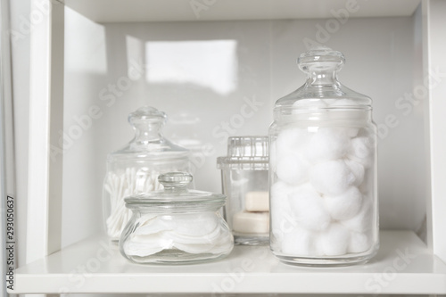 Tablou pe pânză Cotton balls, swabs and pads on white shelf in bathroom
