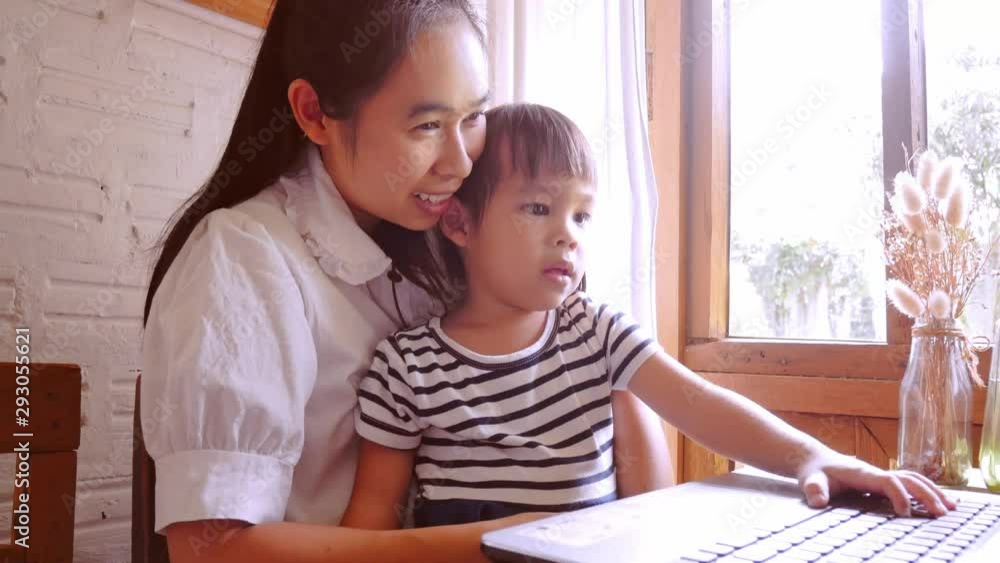 Young mother with daughter look in laptop together in a cafe. Young mother with daughter look in laptop together in a cafe.
