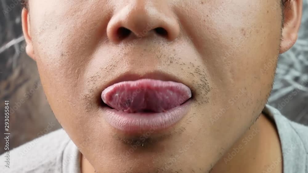 Asian middle aged man making fast tongue out over gray background. Asian middle aged man making fast tongue out over gray background.