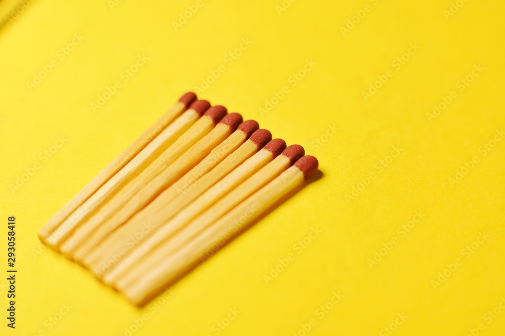 Symbol of danger with matches on yellow background top view , pile of match arrange in a row , unlit matches Symbol of danger with matches on yellow background top view , pile of match arrange in a row , unlit matches