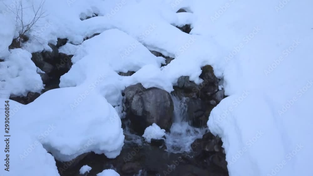 Tilt up view of a little waterfall in a ski resort in Austria surrounded by lots of fresh snow Tilt up view of a little waterfall in a ski resort in Austria surrounded by lots of fresh snow