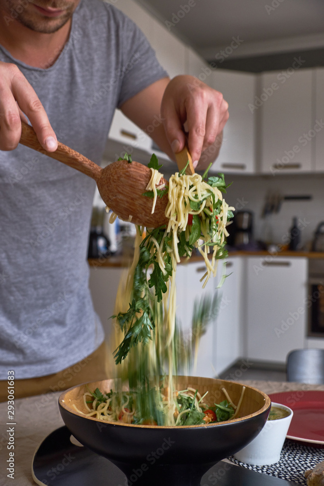 A man stirs pasta in a deep plate