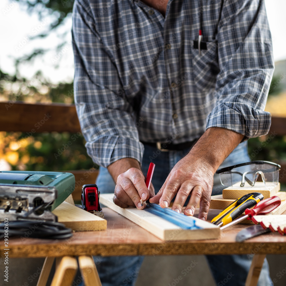 Adult craftsman carpenter with pencil and ruler tracing the cutting line on a wooden table. Housework do it yourself. Stock photography. Adult craftsman carpenter with pencil and ruler tracing the cutting line on a wooden table. Housework do it yourself. Stock photography.