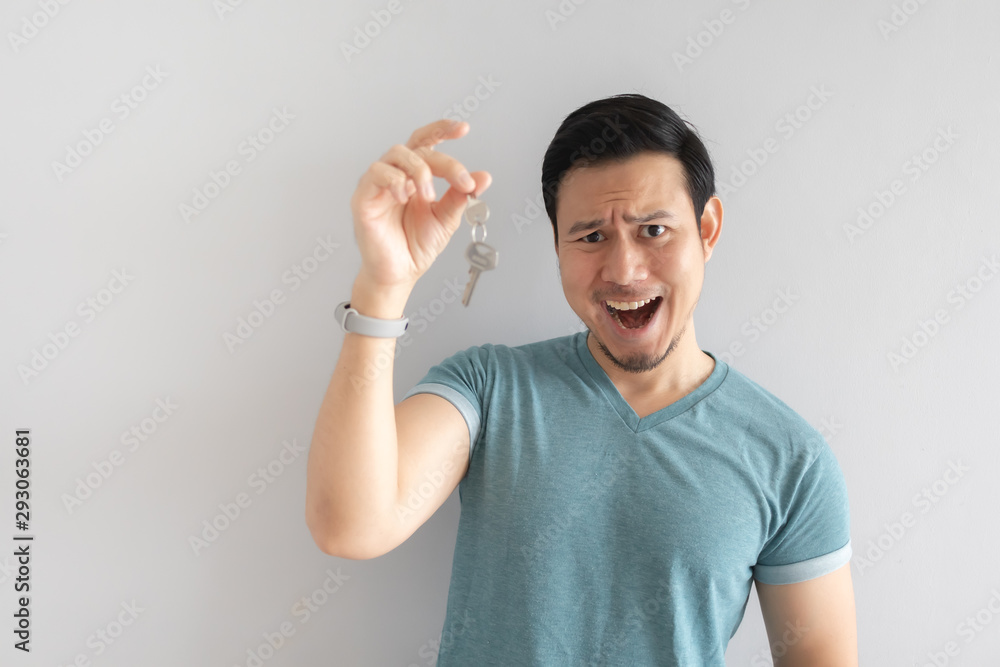 Asian man with funny face showing the key. Concept of useless key.