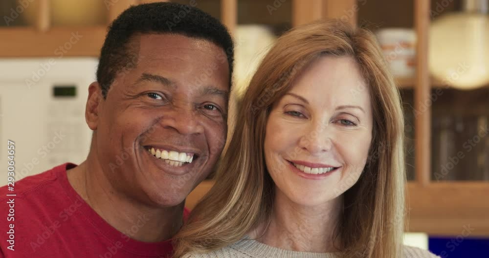 Close up dolly shot of smiling senior African American husband and Caucasian wife in kitchen looking at camera. Tight portrait of happy married couple together. Slow motion 4k Close up dolly shot of smiling senior African American husband and Caucasian wife in kitchen looking at camera. Tight portrait of happy married couple together. Slow motion 4k