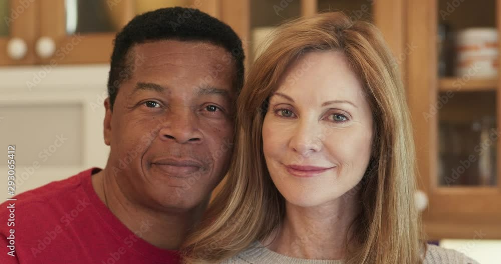 Close up portrait of smiling senior married couple in kitchen looking at camera. Dolly shot portrait of happy African American husband and Caucasian wife together. Slow motion 4k Close up portrait of smiling senior married couple in kitchen looking at camera. Dolly shot portrait of happy African American husband and Caucasian wife together. Slow motion 4k