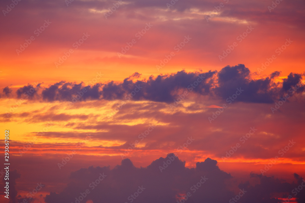 Hermoso cielo con nubes al amanecer con colores vivos, rojos y anaranjados.