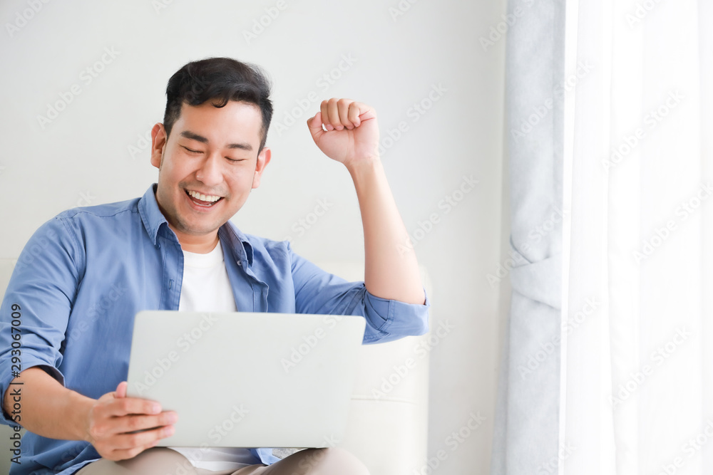 Asian handsome man working with laptop computer in living room happy and smile face Asian handsome man working with laptop computer in living room happy and smile face