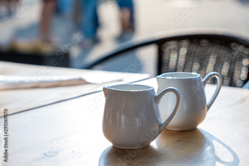Two white cups of coffee on a table of outdoor cafe.