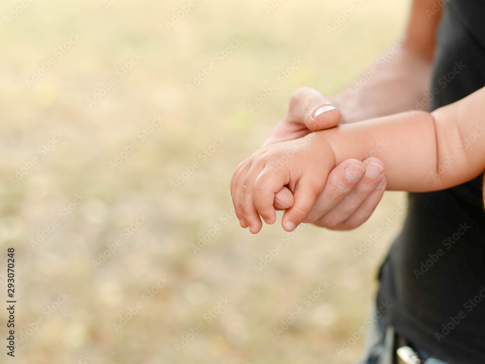 little baby hand with father's hand on light background with copy space, family and childhood concept