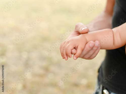 little baby hand with father's hand on light background with copy space, family and childhood concept © Nastya
