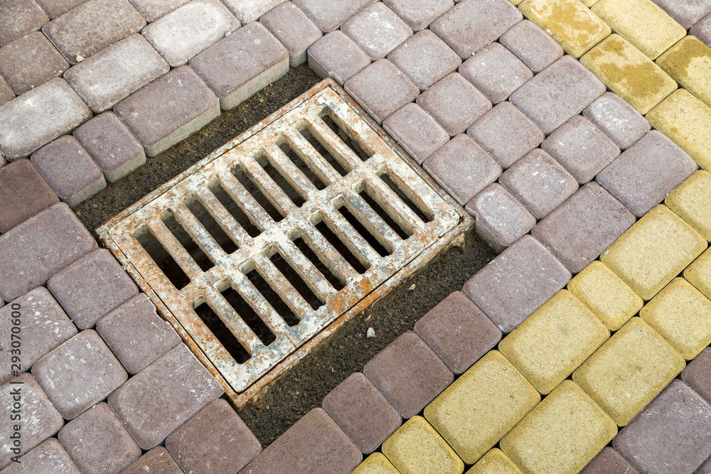 Old rusted metal gutter for rain water on the stone paved sidewalk.
