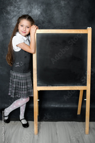 Portrait of a schoolgirl standing next to a black school board
