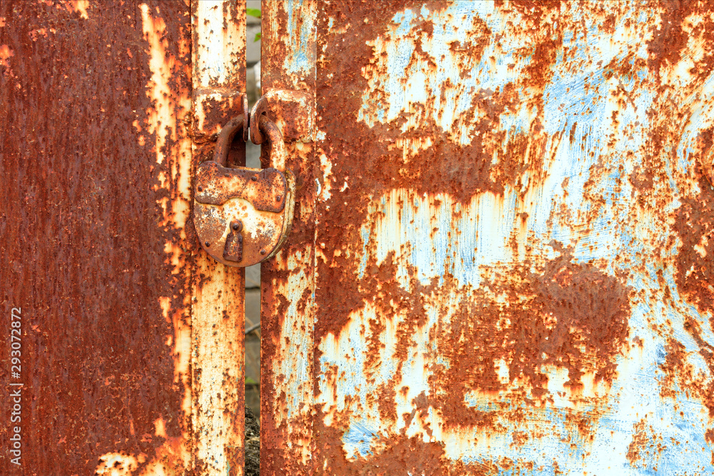 An old rusty lock connects a rusty gate. Rust on old metal sheet texture. An old rusty lock connects a rusty gate. Rust on old metal sheet texture.