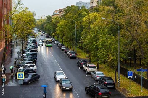 calm city street with cars and pedestrians in rain © hdmphoto