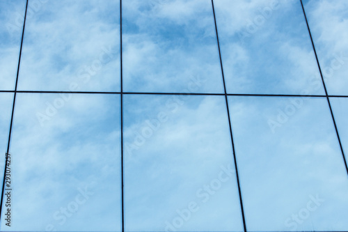 blue sky and clouds reflected in windows of modern building