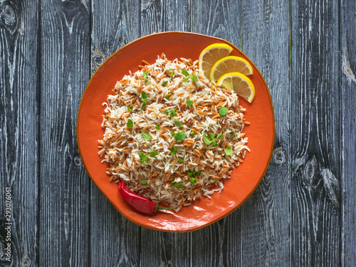 Oriental rice pilaf with orzo in a plate on a dark background. Top view.