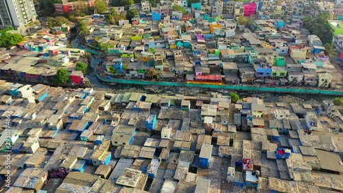 Aerial: Crowded houses in slum by modern residential buildings and sea - Mumbai, India photo