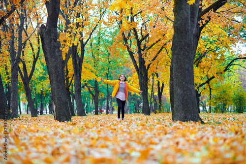 teen girl running with autumn leaves in city park, outdoor portrait