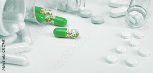 Принти на полотні Closeup on bright green capsules and white pills on white background