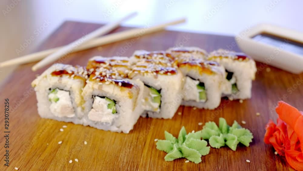 Rolls with fish and sesame seed on top served in wooden board with wasabi, ginger and soy sause Rolls with fish and sesame seed on top served in wooden board with wasabi, ginger and soy sause