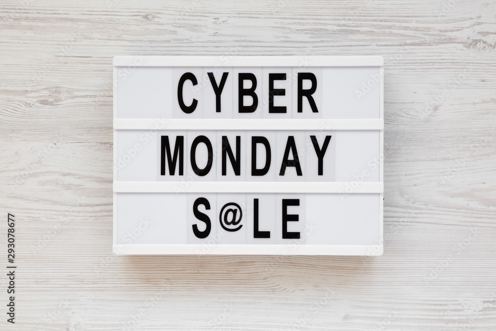 'Cyber monday sale' words on a lightbox on a white wooden background, top view. Overhead, from above, flat lay. Close-up.
