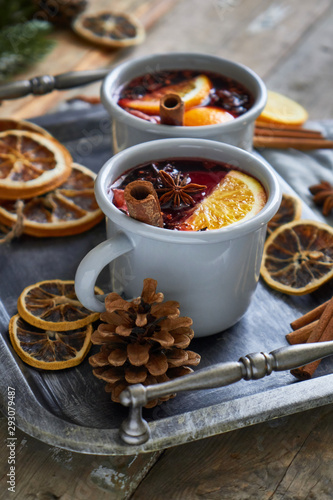 Mulled wine in two gray metall mugs with orange and spices Rustic style On wooden background