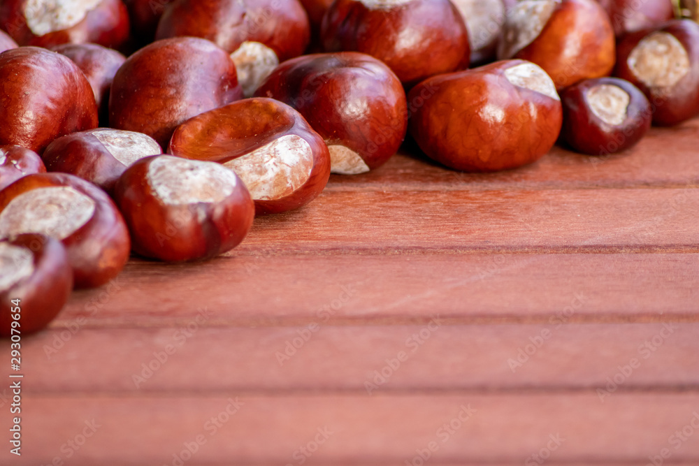 Ein frischer Haufen schöner Kastanien liegt auf einem braunen Tisch bereit zum kreativen Basteln mit Kindern im Herbst und Winter Ein frischer Haufen schöner Kastanien liegt auf einem braunen Tisch bereit zum kreativen Basteln mit Kindern im Herbst und Winter