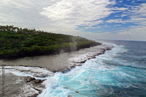 Aerial shot of sea waves are crashing into the rocky cliffs of a desert island before the storm.