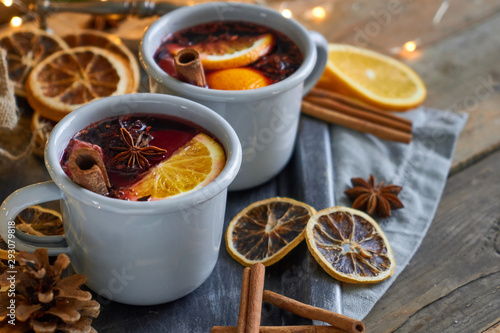 Christmas mulled wine in two rustic mugs with fruits and spices on wooden background