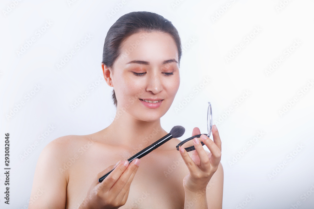 asian woman applying cosmetic powder brush on white background asian woman applying cosmetic powder brush on white background