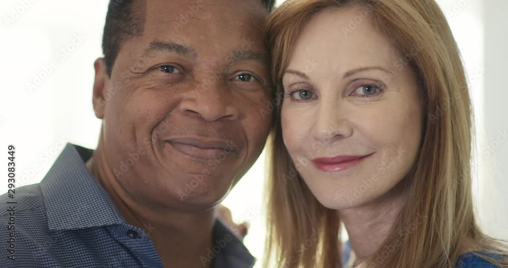 Close up portrait of happy married African American and Caucasian couple smiling by window. Senior husband and wife looking at camera with heads together. Slow Motion 4k Handheld Close up portrait of happy married African American and Caucasian couple smiling by window. Senior husband and wife looking at camera with heads together. Slow Motion 4k Handheld