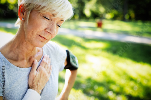 Obraz na plátne Senior woman with chest pain suffering from heart attack during jogging