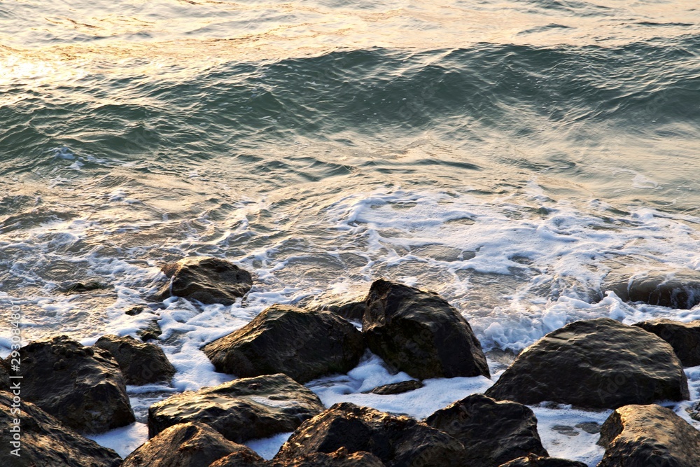 Rocky beach in uae . Waves splashing on rocks in sunny day . beach at the sunset , Waves crashing into the Rocks Rocky beach in uae . Waves splashing on rocks in sunny day . beach at the sunset , Waves crashing into the Rocks