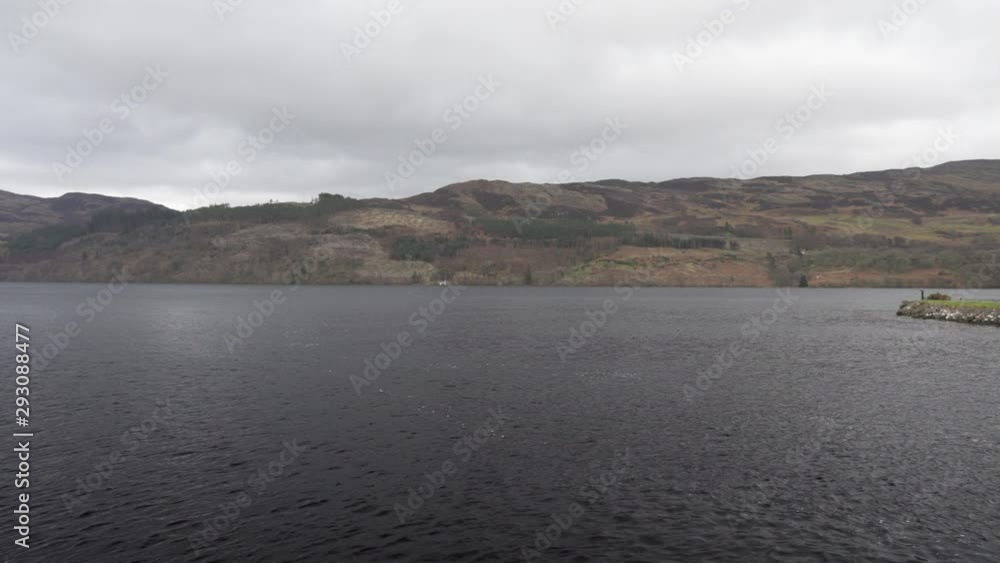 Panning shot from the coast of Loch Ness on the lake and surrounding mountains on a cloudy day in Scotland Panning shot from the coast of Loch Ness on the lake and surrounding mountains on a cloudy day in Scotland