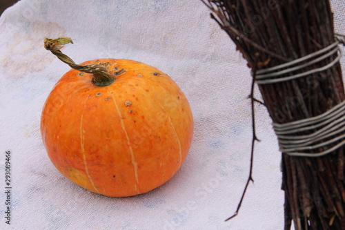 a small orange pumpkin and a broom lie on a white background