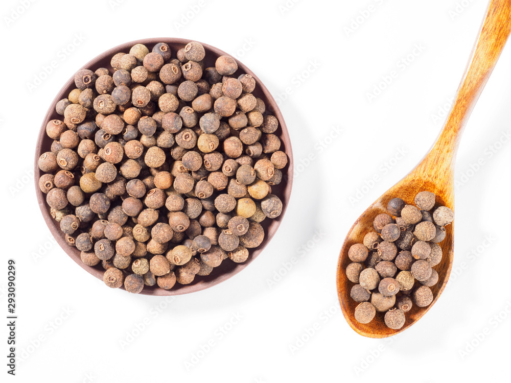 Allspice (Jamaica pepper) in the clay plate and wooden spoon diagonally on white background Allspice (Jamaica pepper) in the clay plate and wooden spoon diagonally on white background