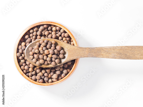 Allspice (Jamaica pepper) in the wooden cup and spoon horizontally on white background