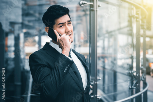 Businessman smiling and talking on phone at sidewalk of the modern building