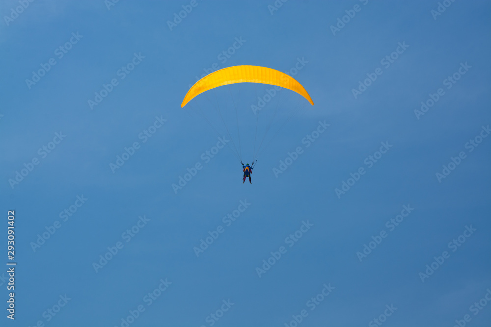 Skydiver with a yellow parachute on a background of blue clear sky Skydiver with a yellow parachute on a background of blue clear sky