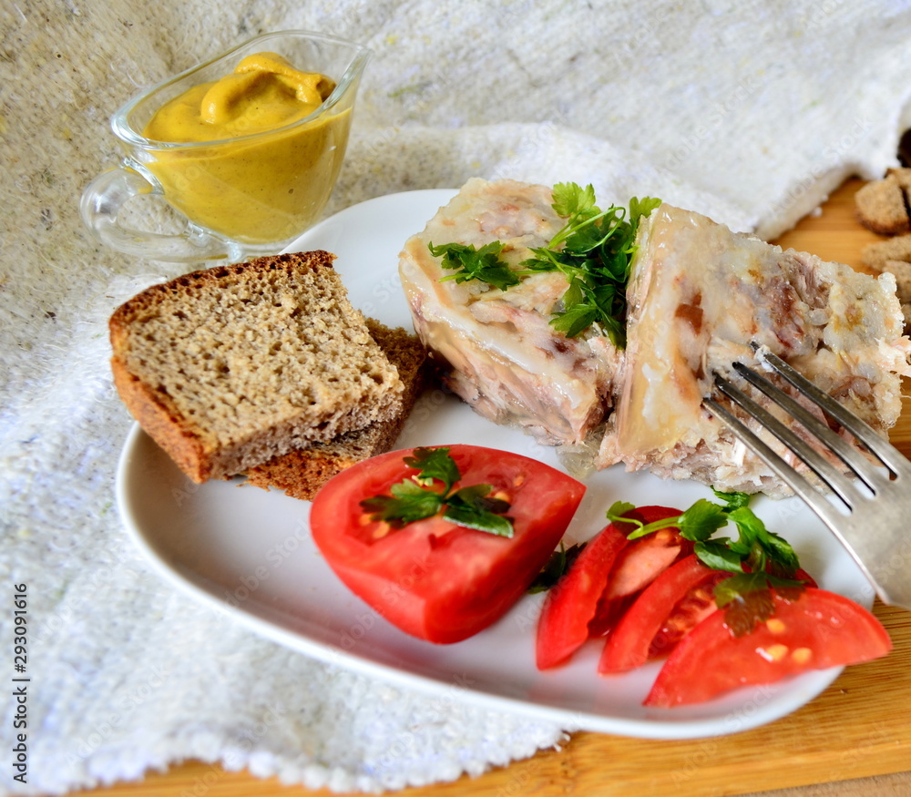 Jelly with meat, beef jelly, traditional Russian dish, serving on a plate, mustard, bread, tomatoes. Side light. Close-up. Jelly with meat, beef jelly, traditional Russian dish, serving on a plate, mustard, bread, tomatoes. Side light. Close-up.