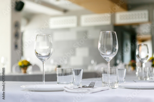 A front view of wine glasses and dishes in the restaurant table set