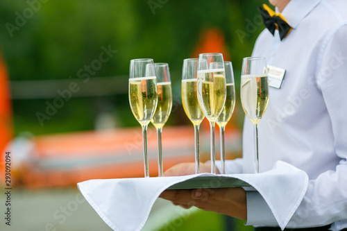 A waiter is serving a few glass of champagne on the tray