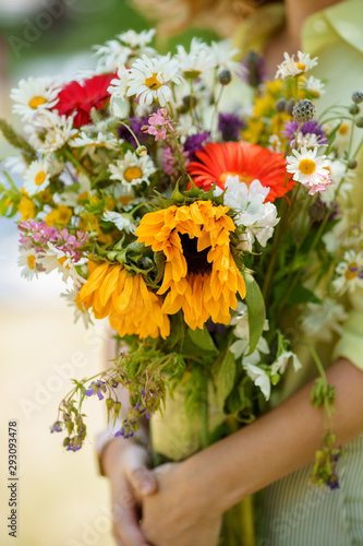 A lady is holding bouquet of wild flowers in her hands