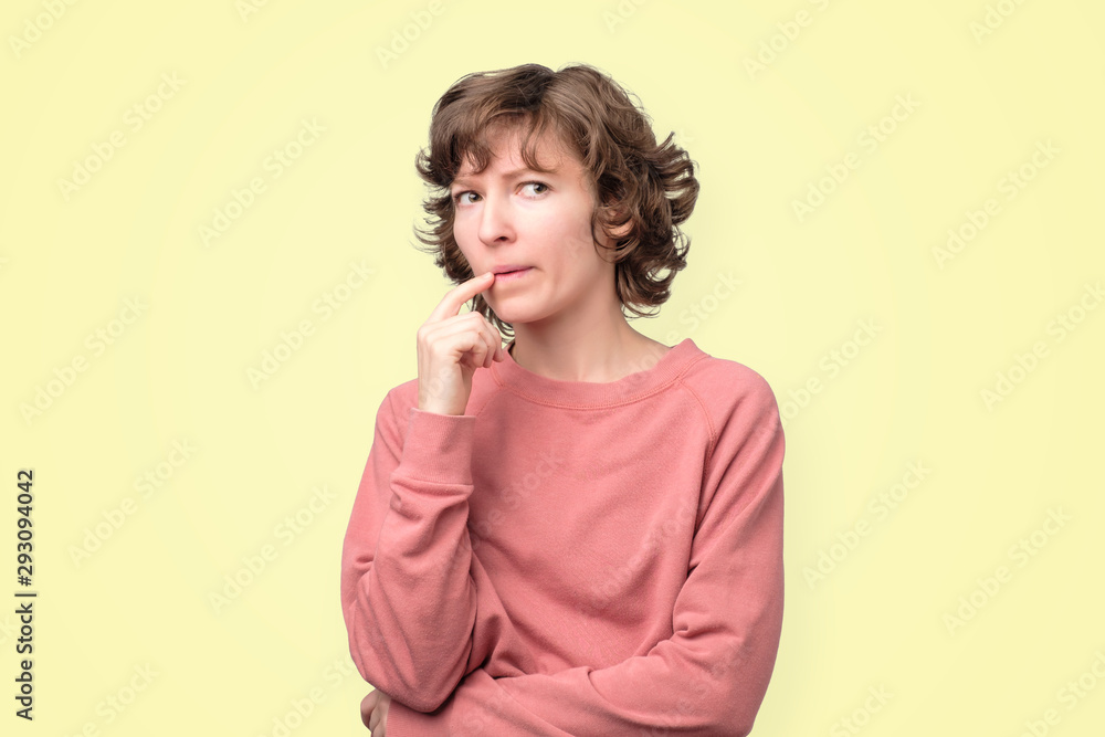 Fototapeta premium Młoda kędzierzawa kobieta myśli i zastanawia się nad czymś